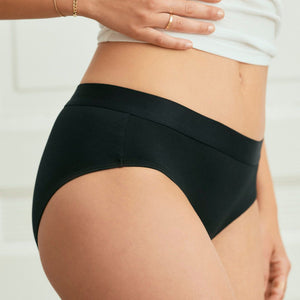 Modell trägt ooia everyday Hipster in Schwarz – Unterwäsche mit breitem Bund, die Slipeinlagen ersetzt. Detailansicht.