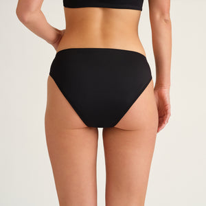 Hip-shot von hinten, eine Frau die einen Schwarzen  Perioden Badeanzug Slip von Ooia trägt