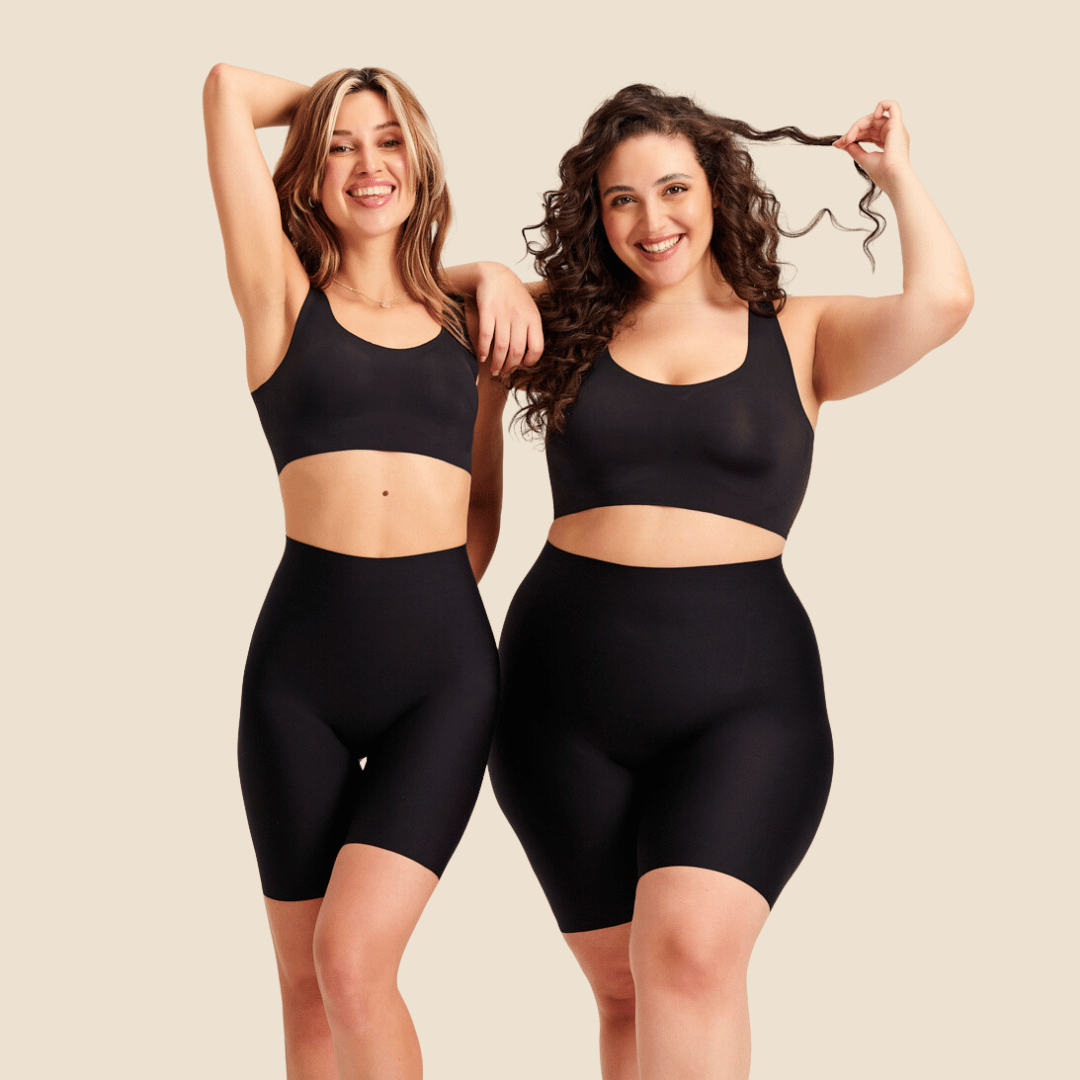 zwei Models posieren lächelnd und tragen dabei ooia Shape Shorts in schwarz und all-you-need Bra Top in schwarz.