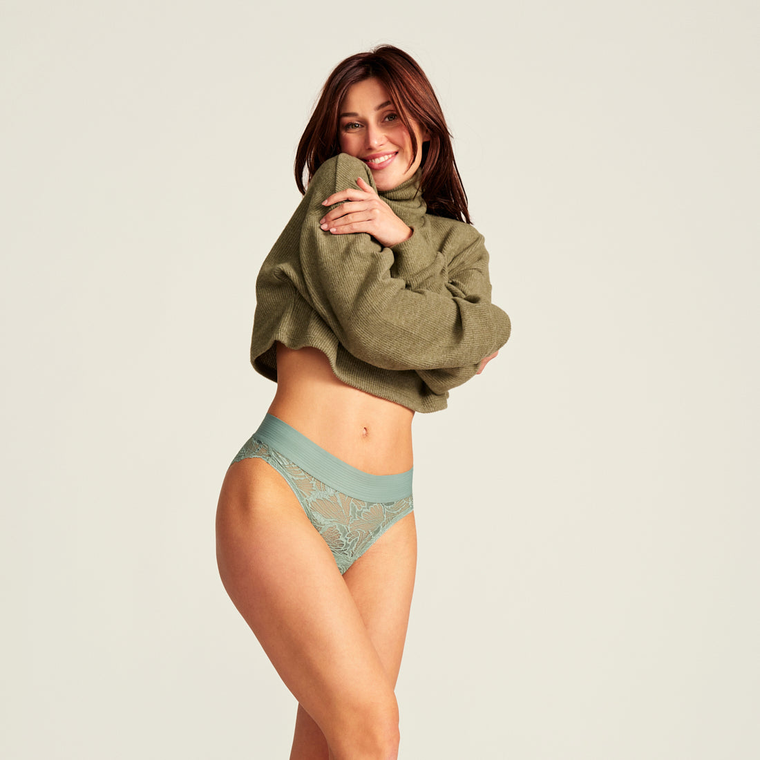 Model posiert in grünen Pullover und grüner Lace Menstruationsunterwäsche von ooia