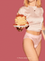 Model trägt ooia Lace Leaf Periodenunterwäsche und hält Pancakes in der Hand