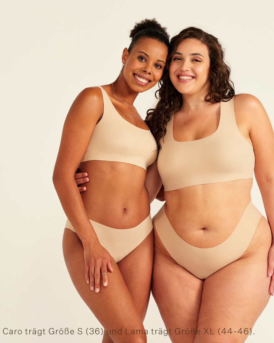 Zwei Models unterschiedlicher Konfektion tragen ooia All-You-Need Bra Top in Beige – bügelloses, nahtloses Bustier mit breiten Trägern, dazu passed Periodenslip Seamless in Beige.