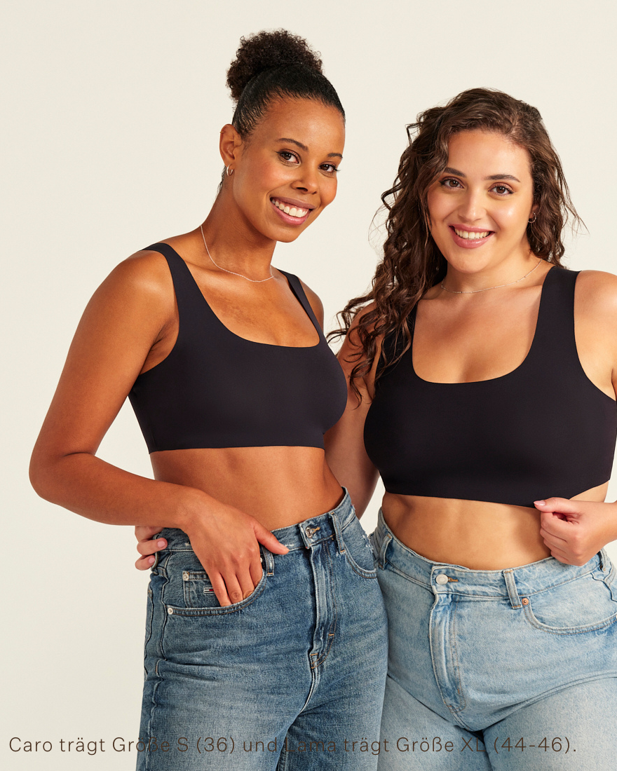 Zwei Models unterschiedlicher Konfektion tragen ooia All-You-Need Bra Top in Schwarz – bügelloses, nahtloses Bustier mit breiten Trägern, dazu Jeans.