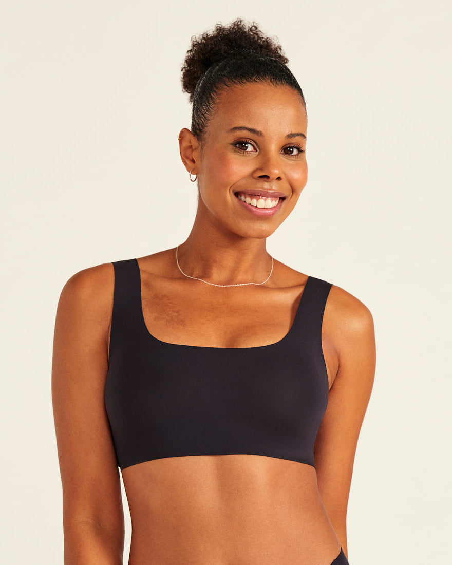 Modell trägt ooia All-You-Need Bra Top in Schwarz – bügelloses, nahtloses Bustier mit breiten Trägern.
