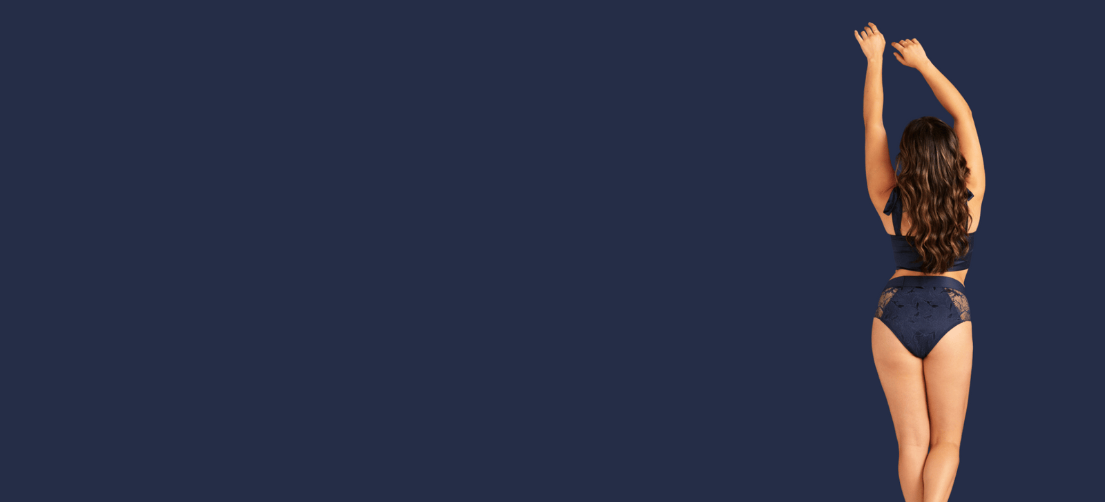 Model steht mit dem Rücken zur Kamera und posiert in dunkelblauer Lace Periodenunterwäsche von ooia.