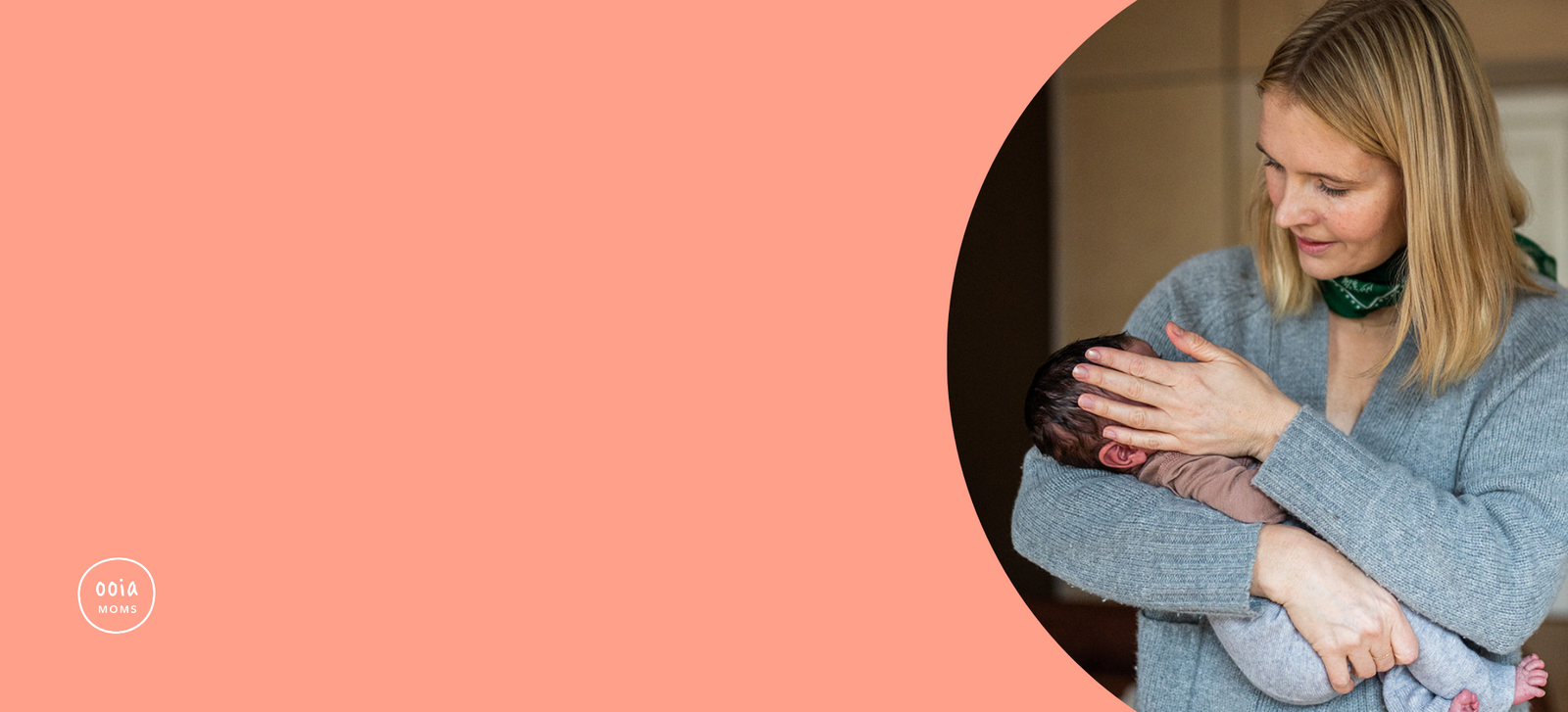 Mutter trägt ihr Baby im Arm und streicht mit der Hand über dessen Wange.