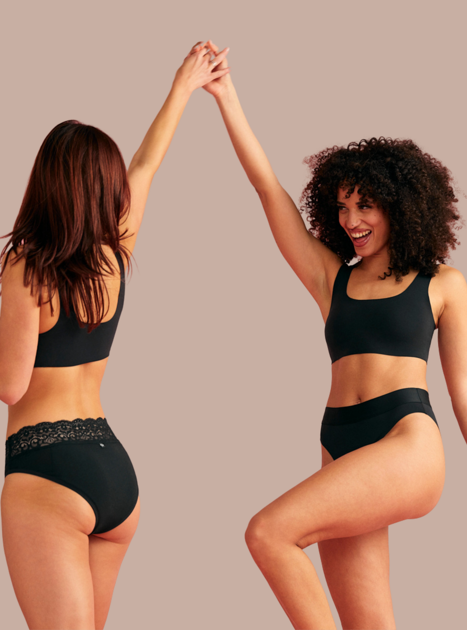zwei Frauen in schwarzer ooia Periodenunterwäsche tanzen und lächeln