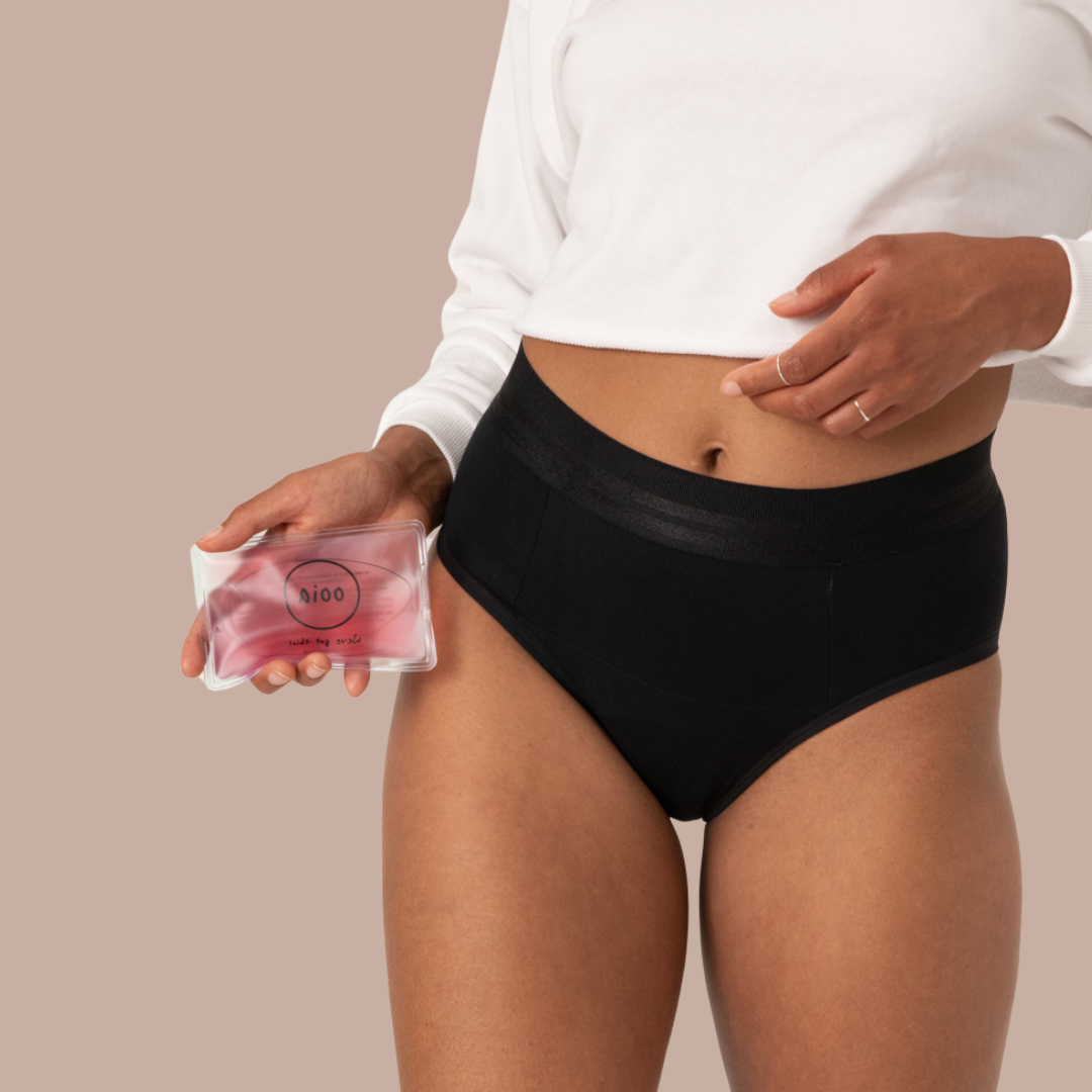 Model trägt schwarze Periodenunterwäsche und hält ein Heatpad dafür