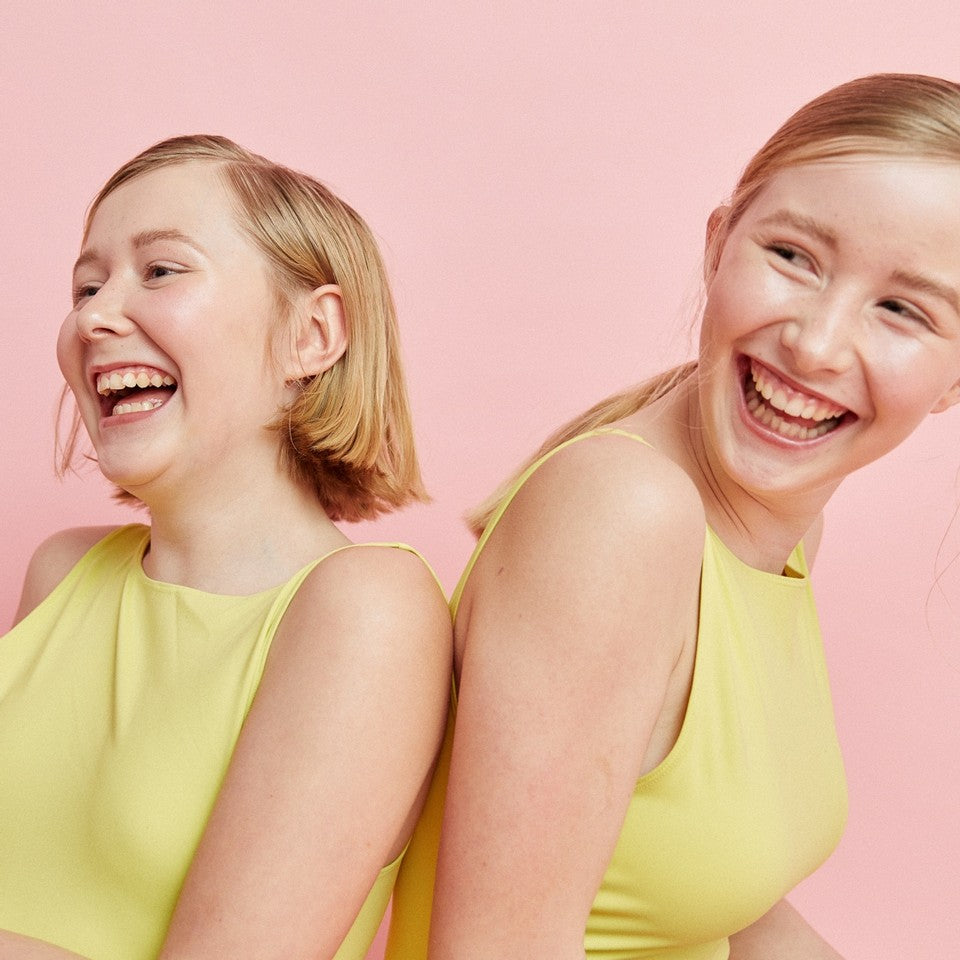 Drei lächelnde Teenager Mädchen halten jeweils einen schwarzen Periodenslip in der Hand.