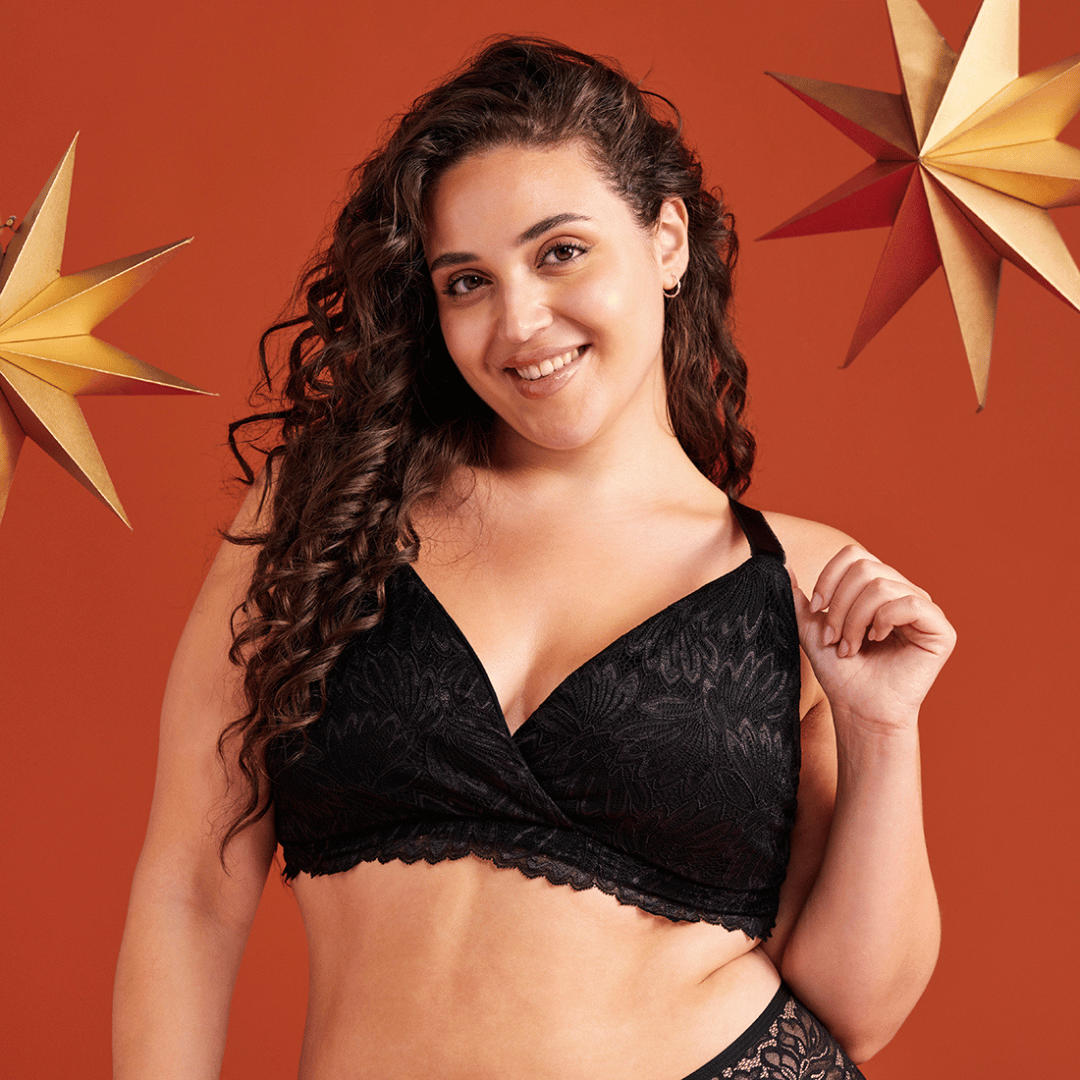 Das Model steht vor weihnachtlichem Hintergrund und trägt den ooia Moms Still BH