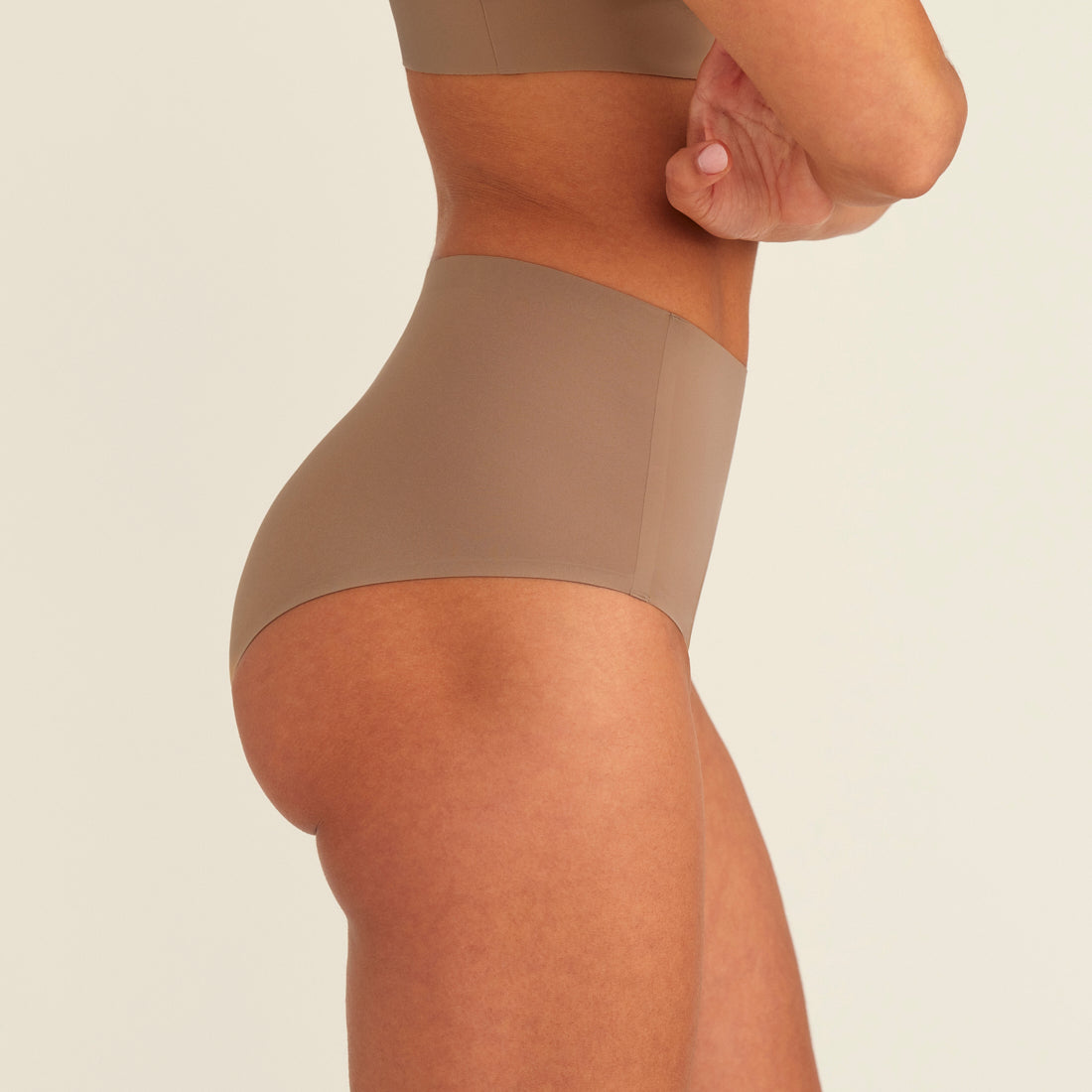 Modell trägt ooia Periodenunterwäsche Highwaist Seamless in Taupe mit hohem Bund und nahtlosem Design