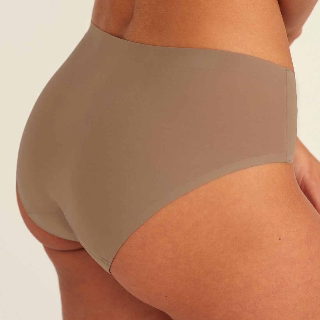 Modell trägt ooia Periodenunterwäsche Hipster Seamless in Taupe mit nahtlosem Design, Detailansicht