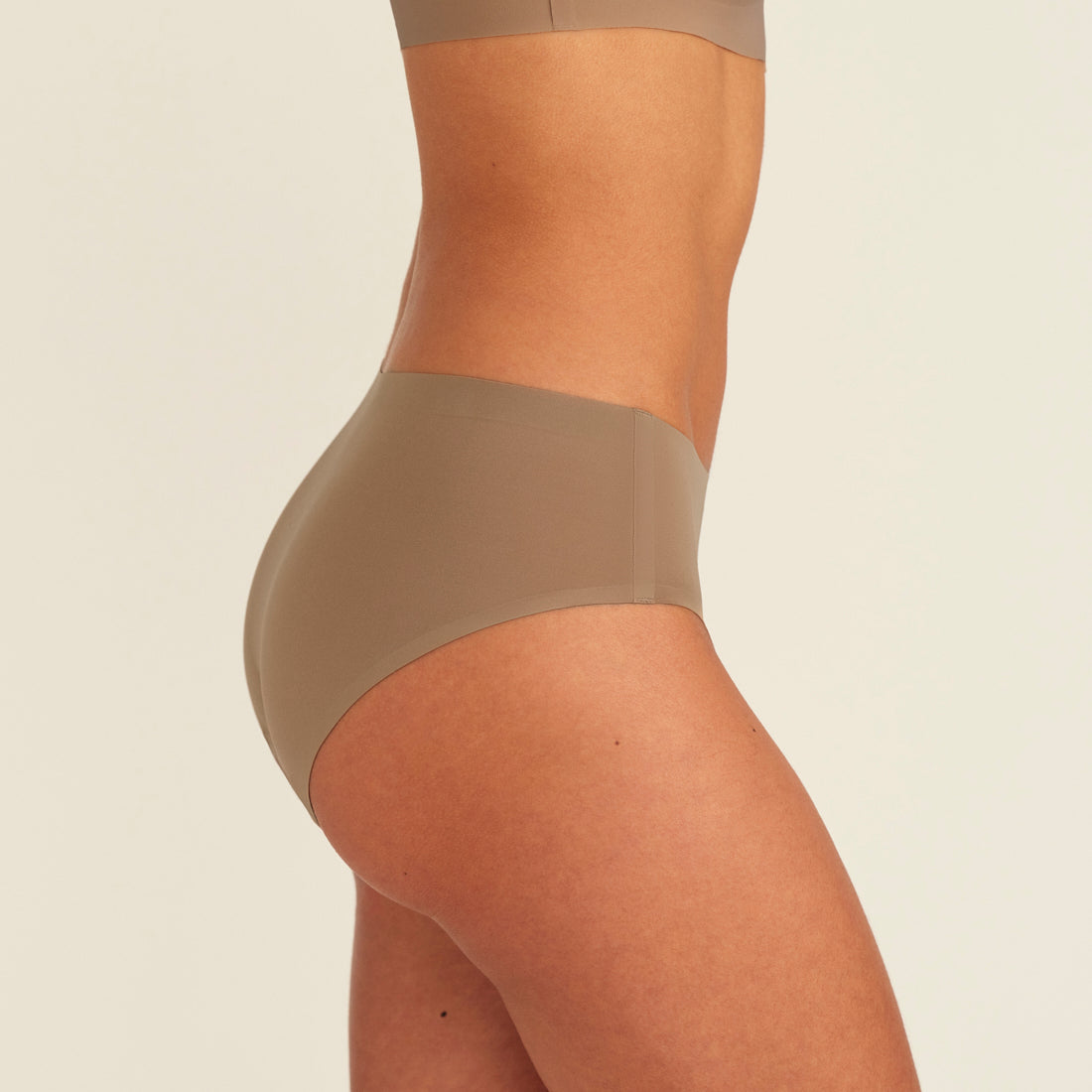 Modell trägt ooia Periodenunterwäsche Hipster Seamless in Taupe mit nahtlosem Design