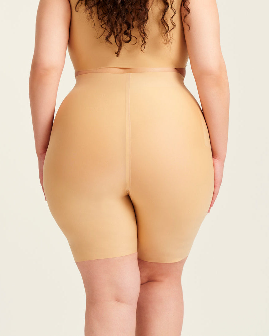 kurviges Modell trägt ooia Shape Short Thigh Saving in Beige – figurformende Short mit Oberschenkelschutz. Rückansicht.