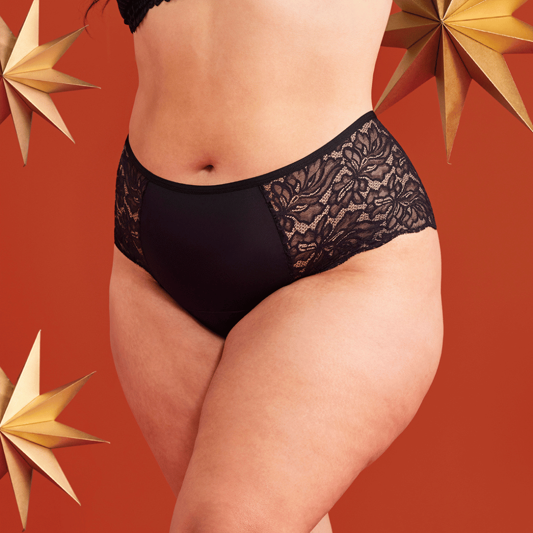 Bildausschnitt eines Lace Periodenslips in schwarz vor weihnachtlichem Hintergrund