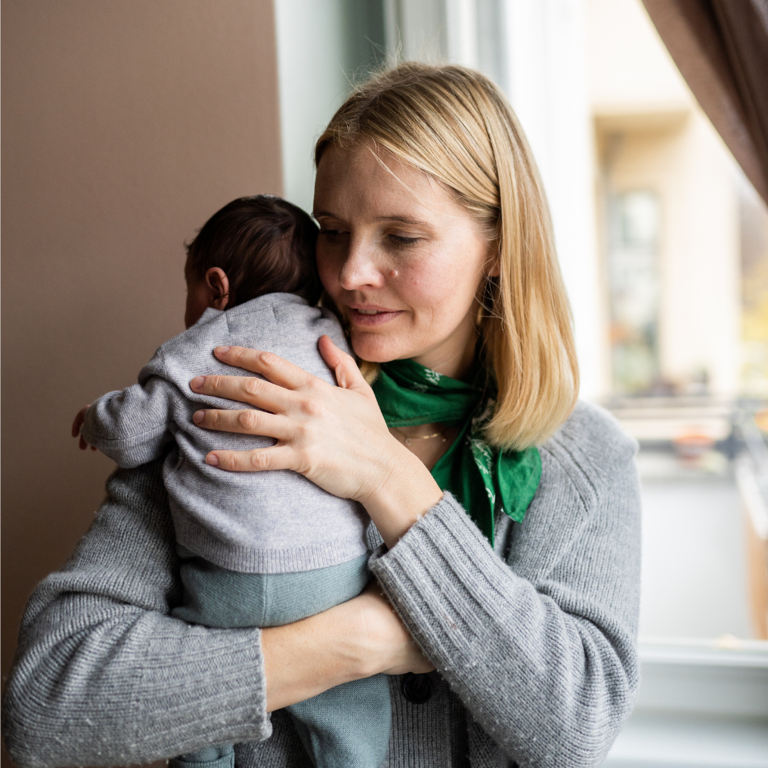 Mutter hält Kind im Arm.