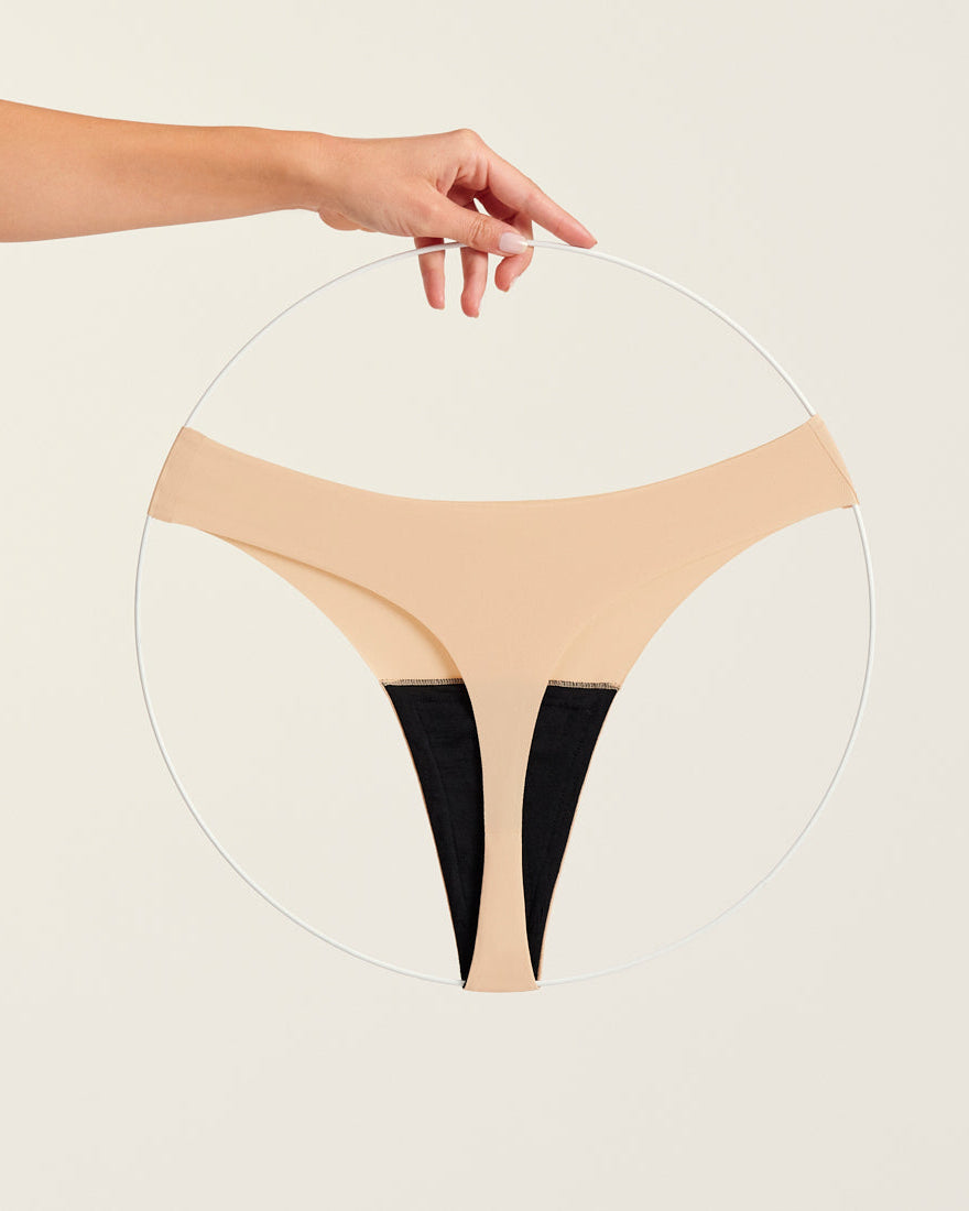 Modell trägt ooia Periodenunterwäsche String Seamless in Beige - nahtloser String mit leichter Saugstärke. Freisteller.