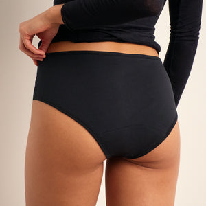Modell trägt ooia Periodenunterwäsche Hipster Comfy Cotton in schwarz aus Baumwolle. 
Hinten