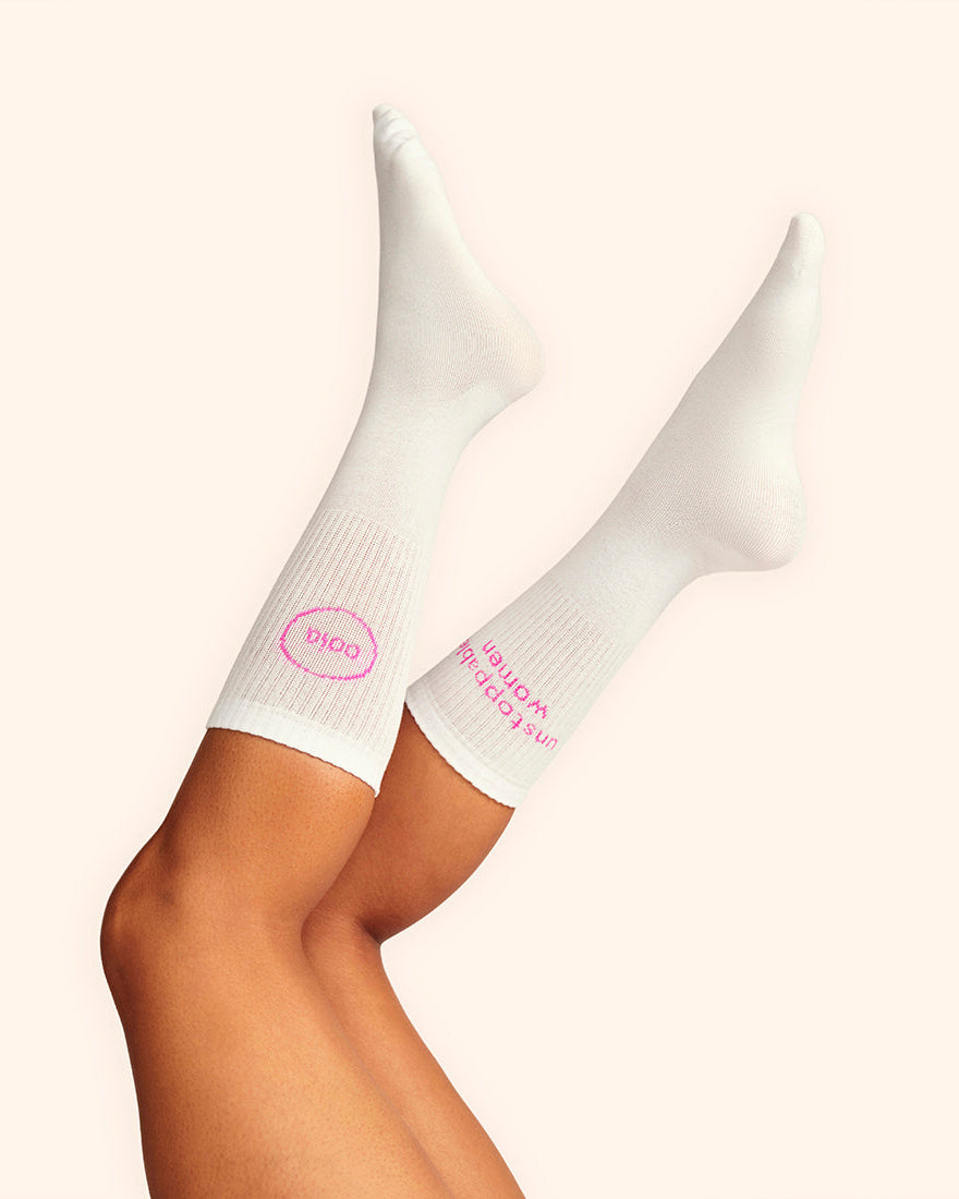 Modell trägt weiße wadenhohe ooia Socken mit dem pinken Aufdruck: Unstoppable Woman