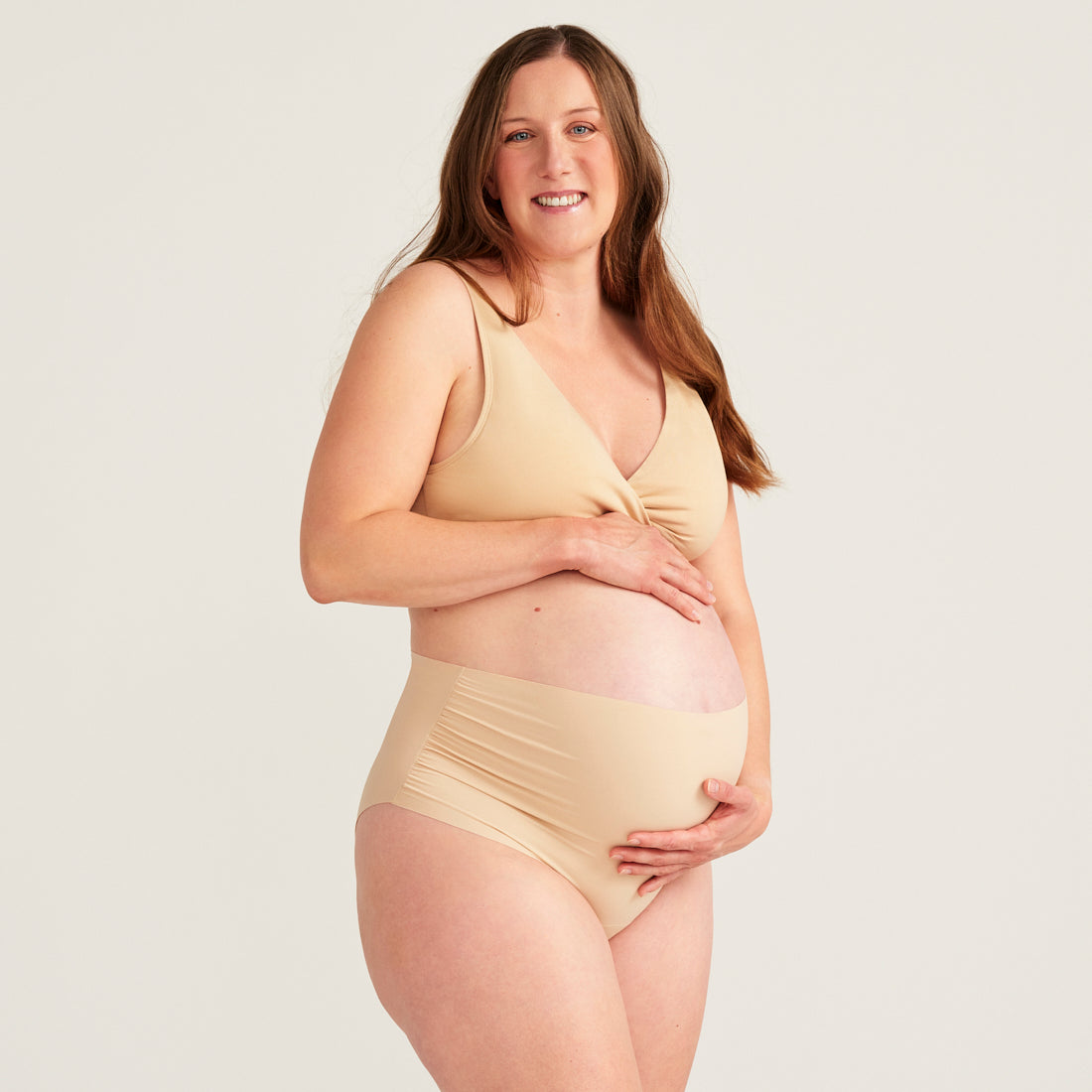 Modell trägt beigen moms Still BH und ooia The Belly Hugger Schwangerschafts-Panty in Beige mit hohem Bund
