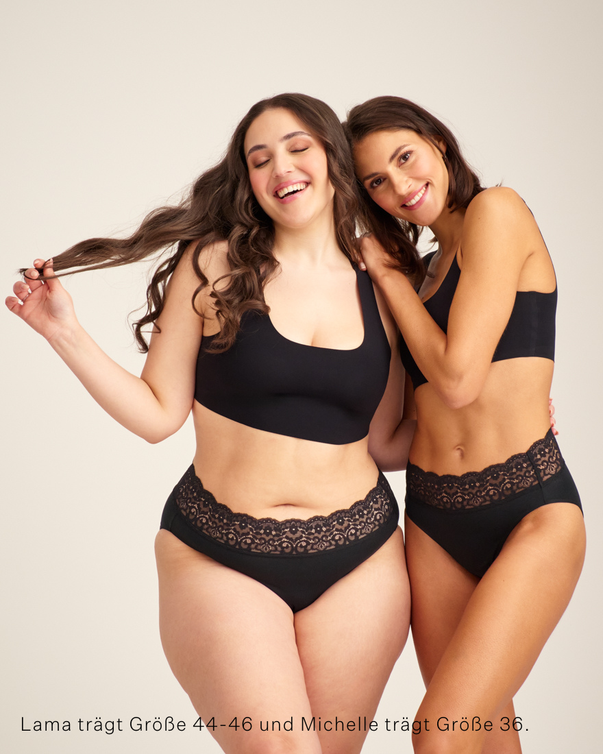 Zwei Models unterschiedlicher kOnfektion tragen ooia everyday Slip in Schwarz – Unterwäsche mit breitem Spitzenbund, die Slipeinlagen ersetzt.