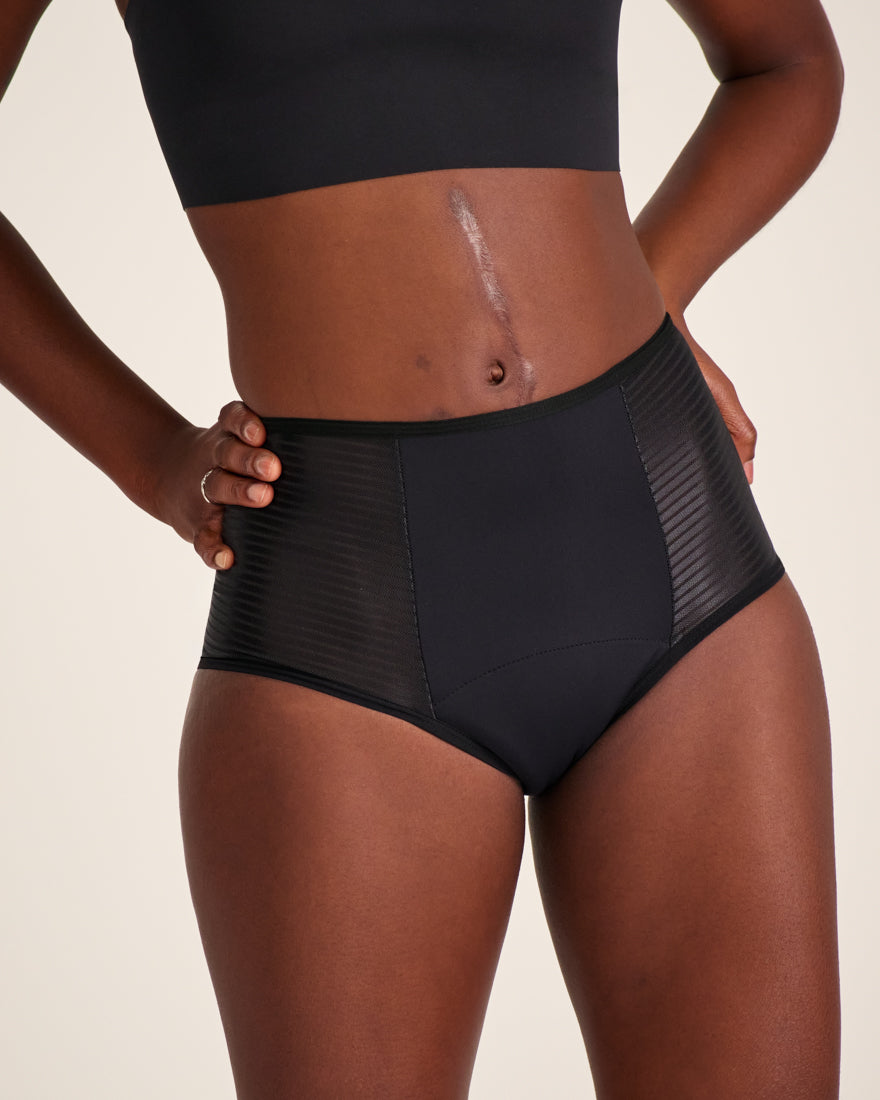 Modell trägt ooia Highwaist Extra Strong in Schwarz – Periodenunterwäsche mit hohem Bund und Glanzdetail.