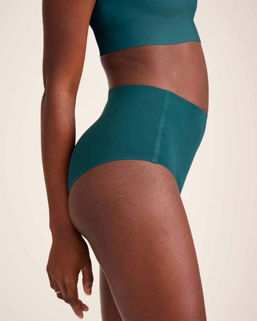 Modell trägt ooia Highwaist Seamless in Grün – nahtlose Periodenunterwäsche mit hohem Bund.