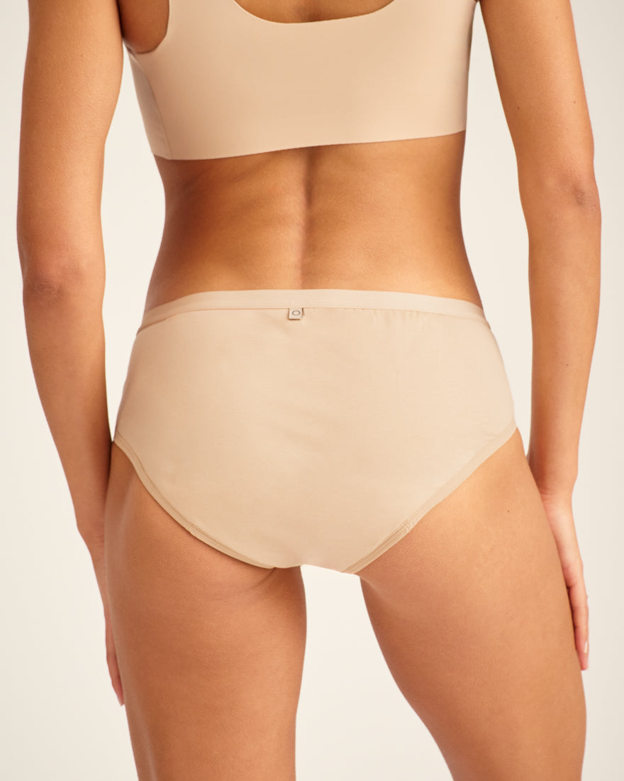 Modell trägt ooia Hipster in Beige – Periodenunterwäsche. Rückansicht.