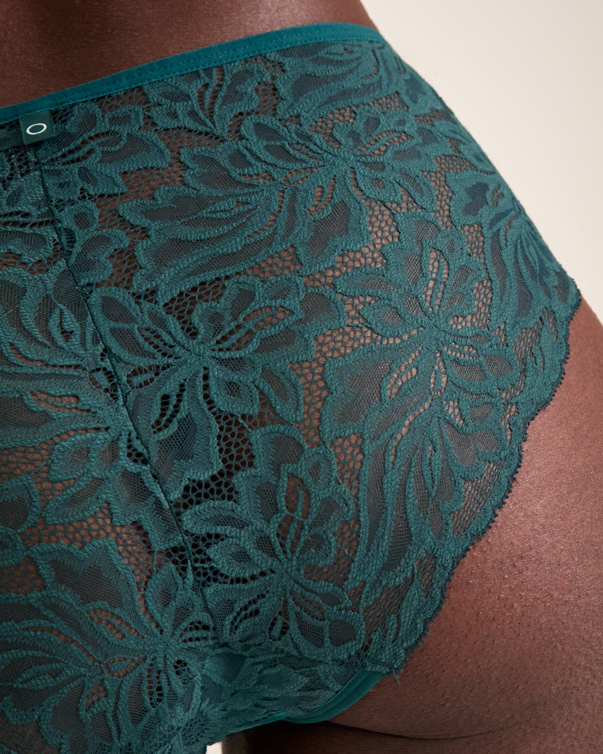Modell trägt ooia Hipster Allover Lace in Grün – elegante Periodenunterwäsche mit durchgehender Spitze. Detailansicht.