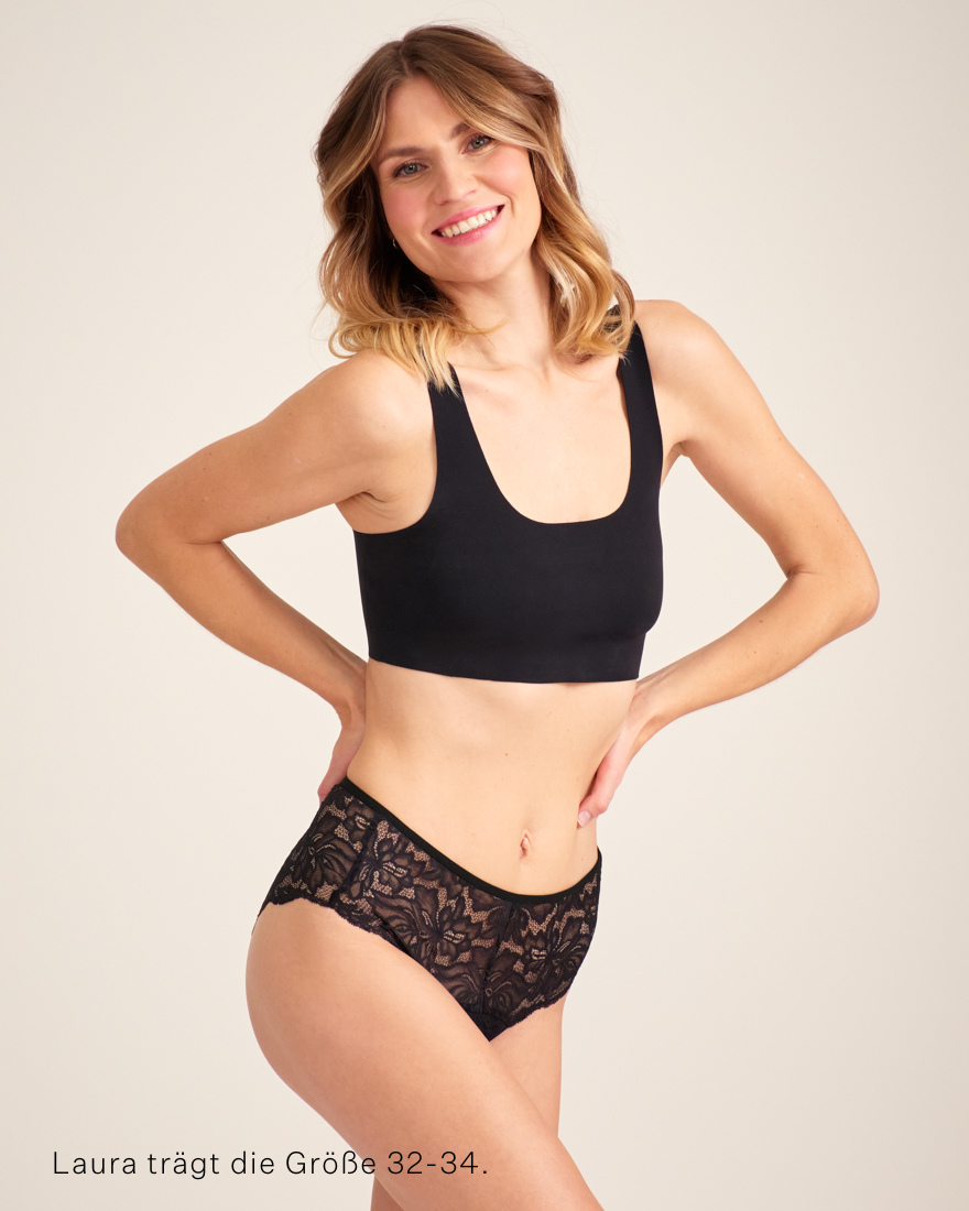Modell trägt ooia Hipster Allover Lace in Schwarz – elegante Periodenunterwäsche mit durchgehender Spitze.