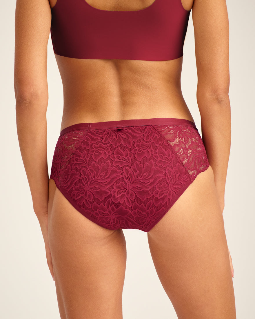 Modell trägt ooia Periodenunterwäsche Hipster Allover Lace in Merlot, mit extra starker Saugstärke und durchgehender Spitze. Rückansicht.