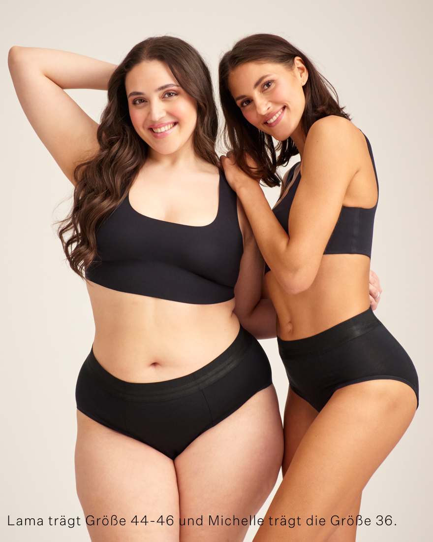 Zwei Models tragen ooia Slip Hugs Extra Strong in Schwarz – bequemer Slip mit extra stützendem Bund, starker Sauglstärke und integrierten Taschen für das ooia Wärmepad.