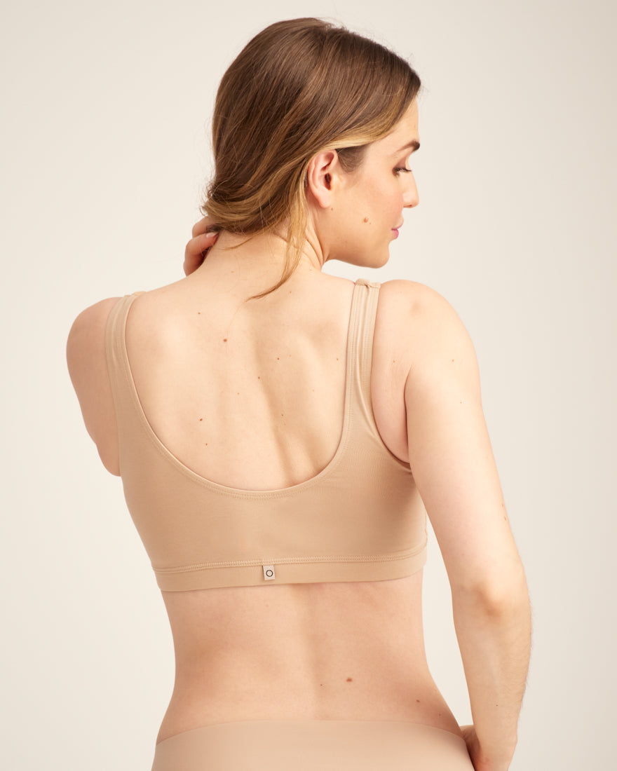 Modell trägt ooia Moms Still-BH in Beige – Still-BH ersetzt Stilleinlagen mit praktischer Pull-Down Funktion. Rückansicht.