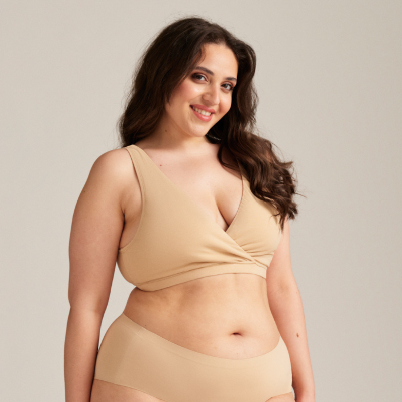 Model trägt einen absorbierenden Still-Bh, der Stilleinlagen ersetzt in beige und kombiniert ihn mit dem Highwaist Seamless beige