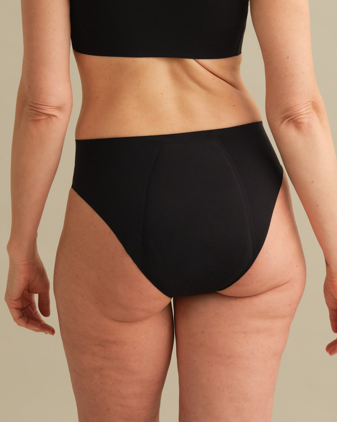 Model trägt ooia Inkontinenz Slip in schwarz in nahtlosem Design.
back