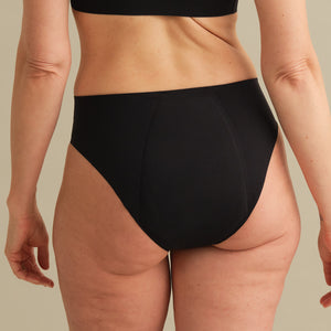 Model trägt ooia Inkontinenz Slip in schwarz in nahtlosem Design.
back