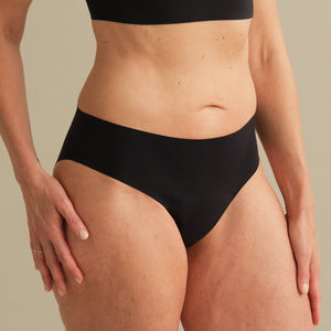 Model trägt ooia Inkontinenz Slip in schwarz in nahtlosem Design.
seitlich
