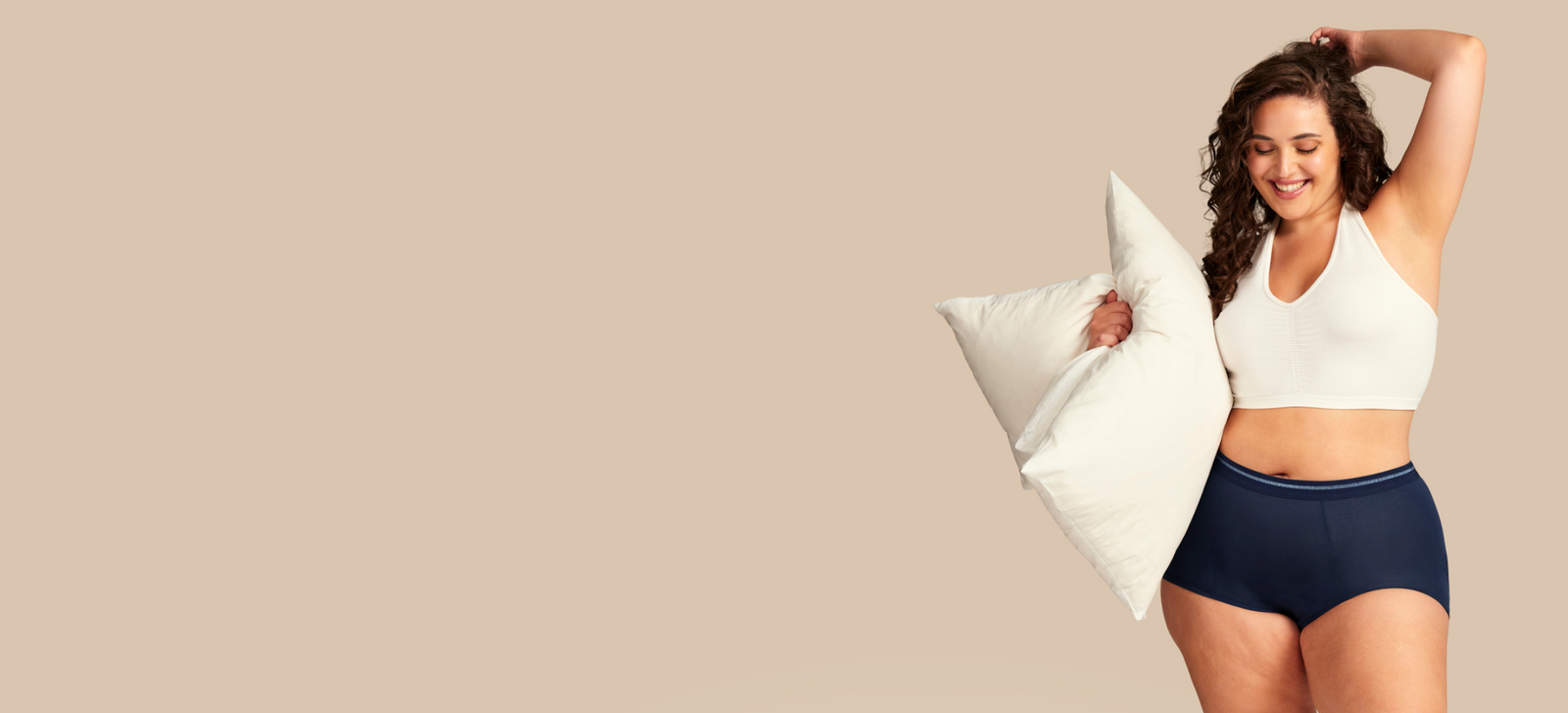 Model in Periodenunterwäsche Shorty in dunkelblau hält Kissen unter dem Arm