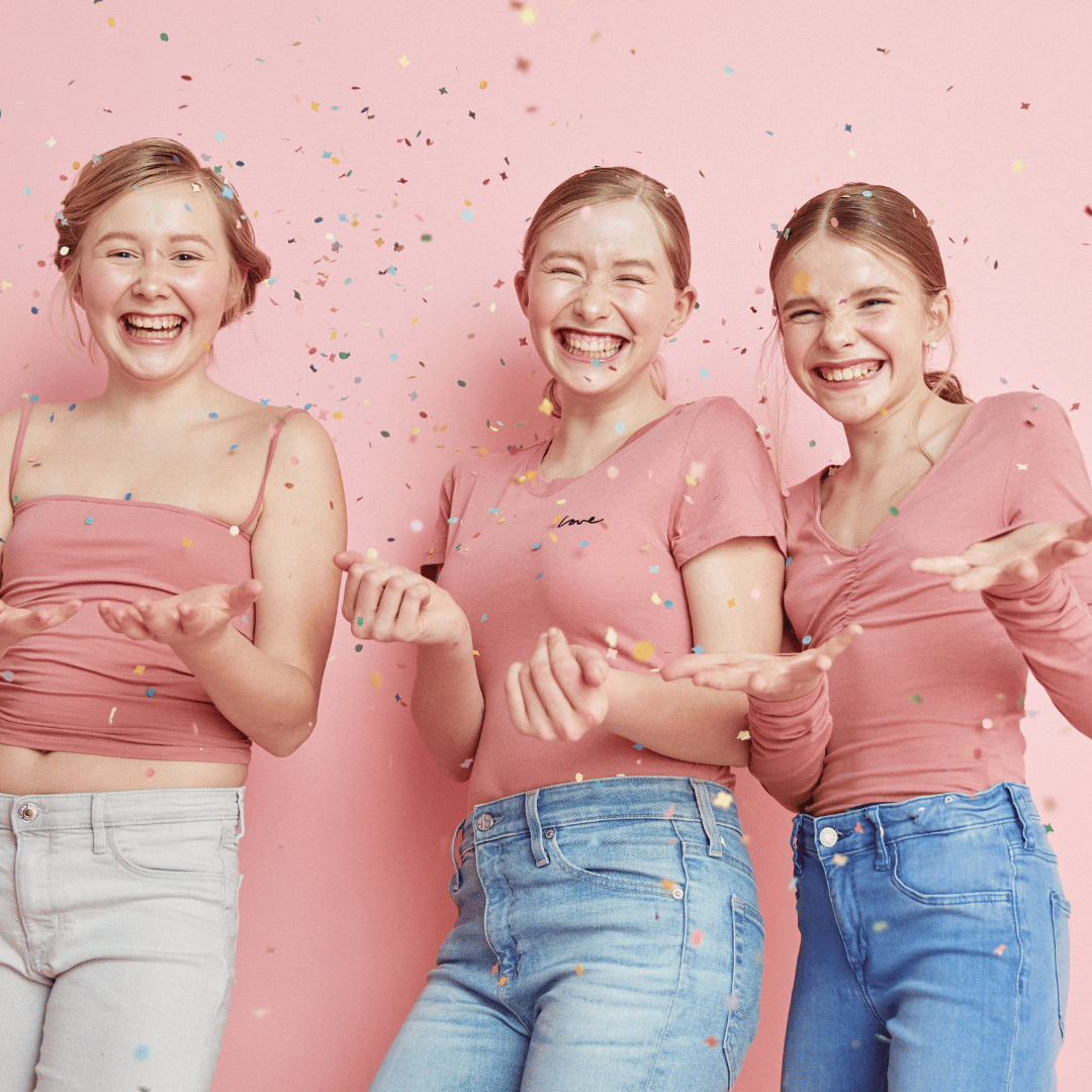 Drei Teenager Mädchen schmeißen Konfetti in die Luft