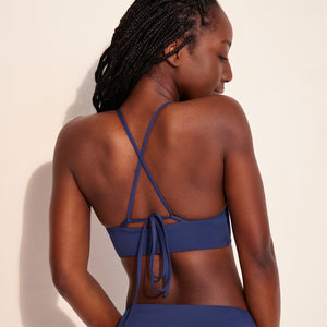 Modell trägt ooia Beach Triangle Top in Ozeanblau –  Bikini-Top im klassischen Triangle Shape mit verstellbaren Trägern. Rückansicht.