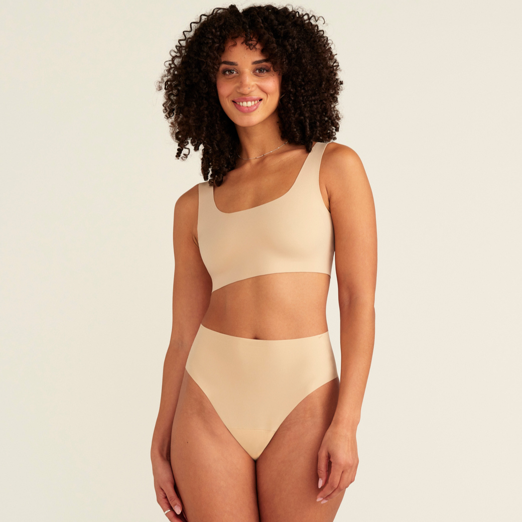 Modell trägt ooia Perioden Highwaist Seamless Cheeky in Beige – nahtloser Slip mit hoher Taille und Beinausschnitt