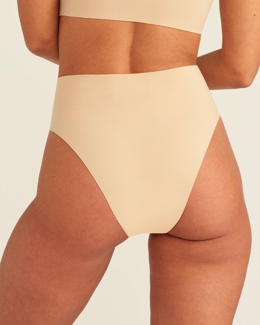 Modell trägt ooia Perioden Highwaist Seamless Cheeky in Beige – nahtloser Slip mit hoher Taille und Beinausschnitt, Rückansicht