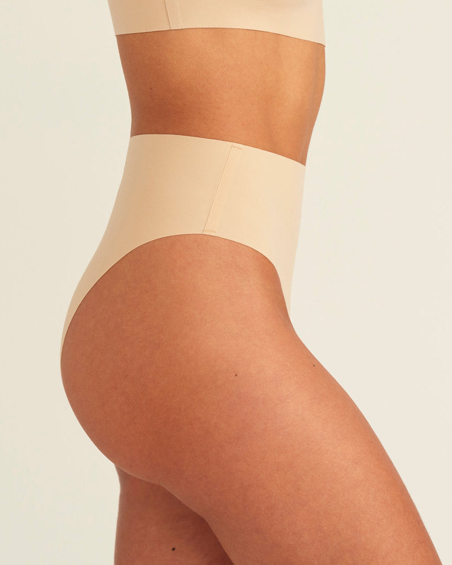 Modell trägt ooia Perioden Highwaist Seamless Cheeky in Beige – nahtloser Slip mit hoher Taille und Beinausschnitt