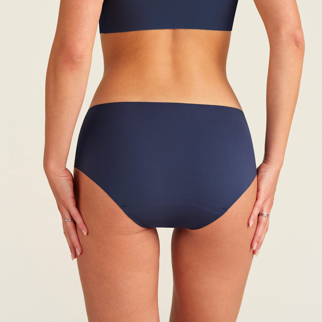 Modell trägt ooia Periodenunterwäsche Hipster Seamless Extra Strong in midnight mit nahtlosem Deign, Rückansicht