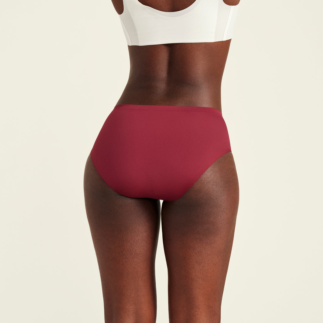Modell trägt Hipster Seamless in Merlot - nahtlose Periodenunterwäsche von ooia. Rückansicht.