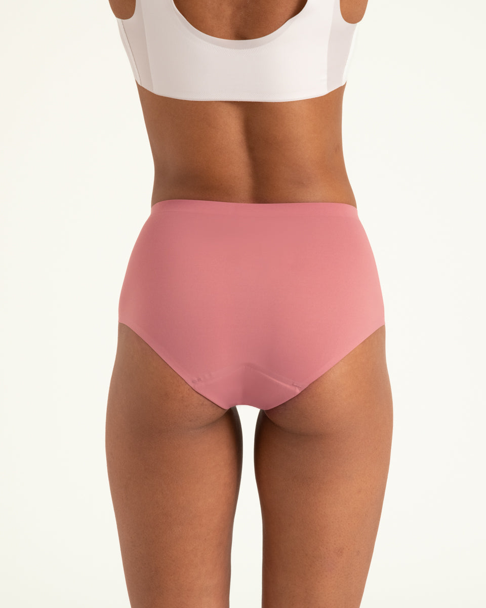 Modell trägt ooia Highwaist Seamless in Dusky Pink – nahtlose Periodenunterwäsche mit hohem Bund. Rückansicht.