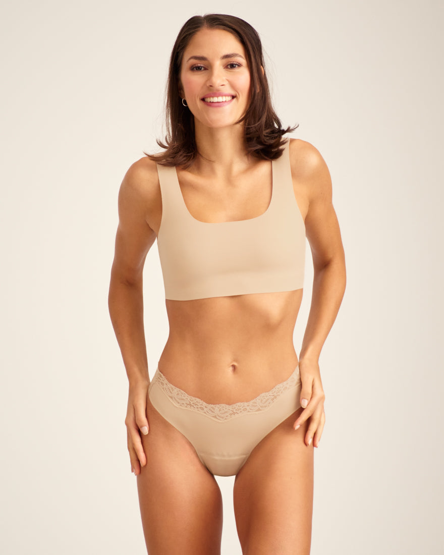Modell trägt ooia Periodenunterwäsche Slip Seamless Lace Extra Strong in Beige