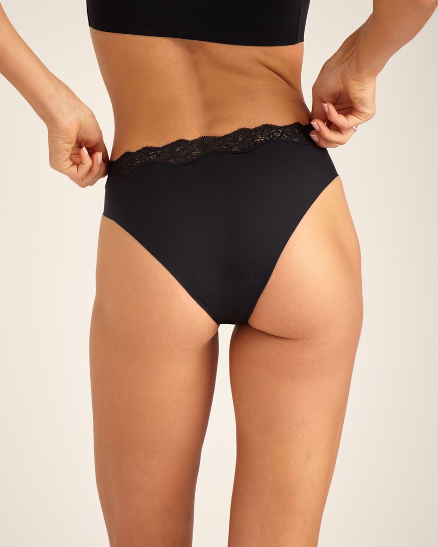 Modell trägt nahtlosen ooia Periodenunterwäsche Slip Seamless Lace Extra Strong in schwarz, Rückansicht