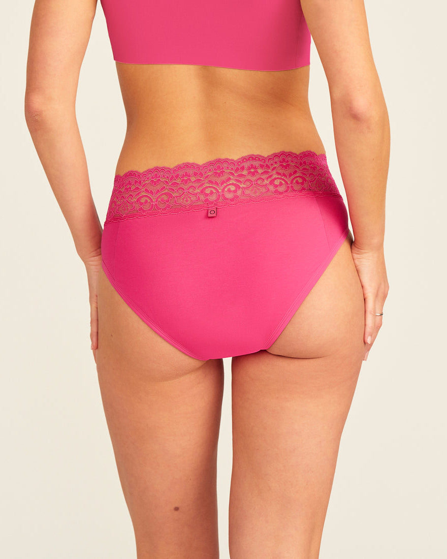 Modell trägt ooia Slip Extra Strong in hot pink mit Spitze am Bund – Periodenunterwäsche für starke Tage, Rückansicht