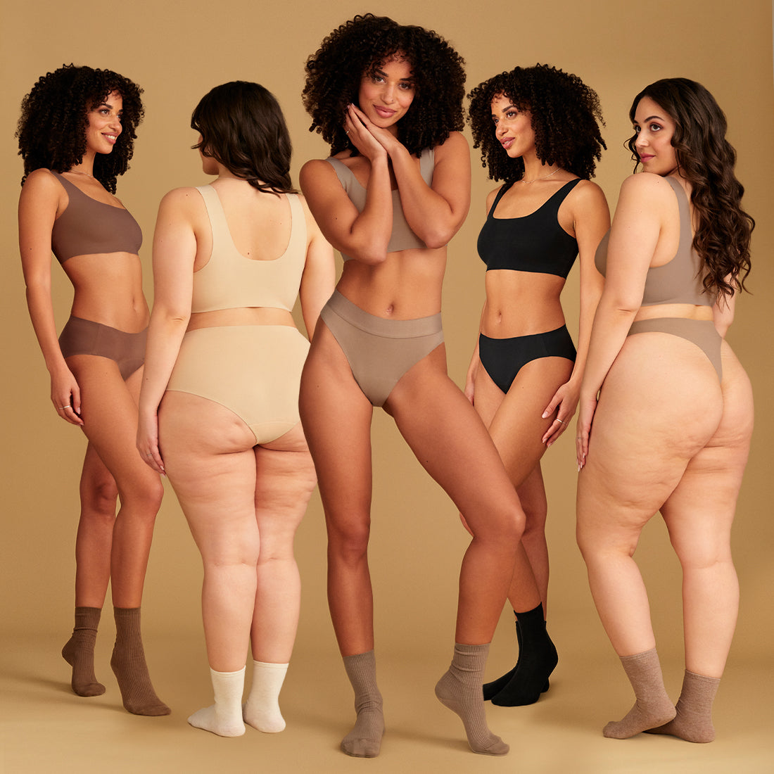 Models tragen nahtlose Periodenslips in verschiedenen Hauttönen von ooia und dazu passende Socken